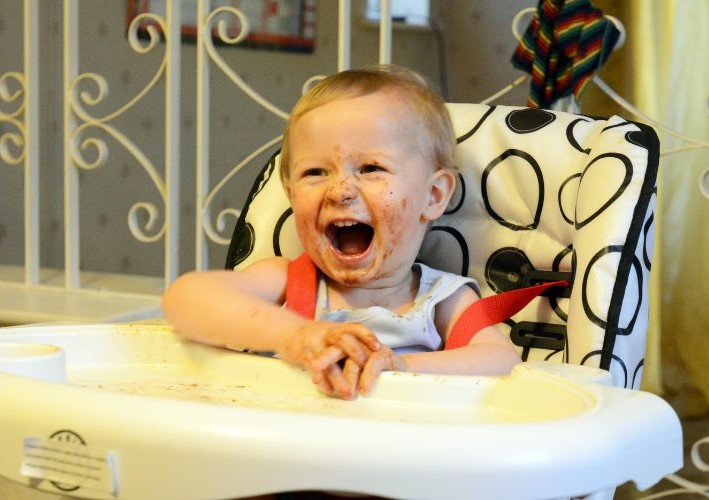 laughing kid with food all over his face