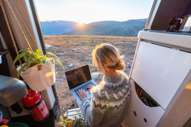 A woman working in her van with a view of the mountains
